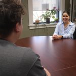 Gabrielle Wilson smiles as she sits across from a student at a boardroom table.