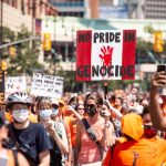 Rally participants hold up signs and wear orange shirts as they march in support of residential school survivors and the families of missing and murdered Indigenous children in Winnipeg on. July 1, 2021. THE CANADIAN PRESS/Mike Sudoma