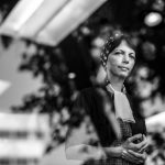 Zahra stands in a reflected window with a pensive face.