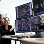 Two people analyzing an image on a screen. Photo taken pre-pandemic.
