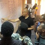 Dr. Robert Lorway points out information on a bulletin board to four Kenyan activists who are gathered around him.