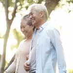 A mature couple walks through the park holding hands