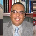 A professional photo of Ehab El-Salakawy sitting, posing and smiling for the camera in front of a book shelf.