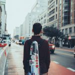 Gregory Lewis stands with his instrument case on a hazy street.