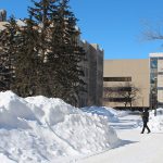 A person wearing a mask walks on Fort Garry campus in winter 2022. // Photo by Jack Rach