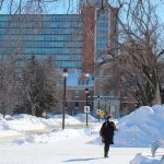 Person wearing mask walks on Fort Garry campus in winter 2022. // Photo by Jack Rach