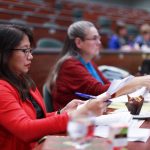 People with notes sitting in a lecture hall.