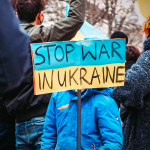 Child holding sign "Stop War in Ukraine" in the middle of a protest