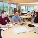 Three students studying at a table together.