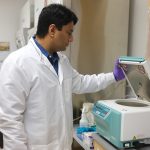 Dr. Abdullah Al Maruf lifts the lid of a microcentrifuge and looks inside.