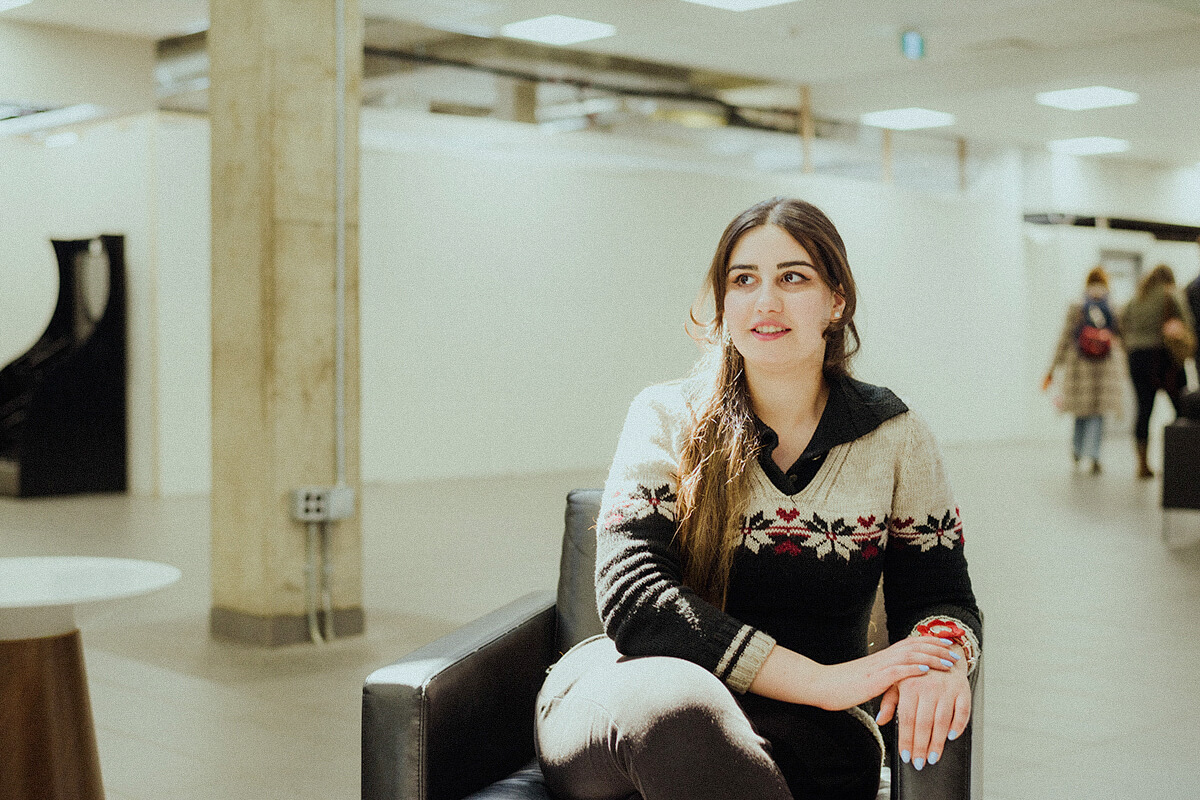 Rose sits in a chair in a university hallway.