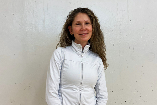 Nicole Evans standing in front of a white wall with a white sweater on.