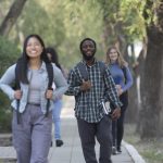 Students walking on campus with trees in background.