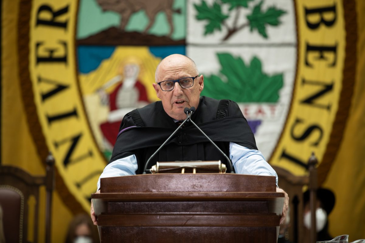 Dr. Brian Postl stands at the podium, speaking at 2022 Spring Convocation.