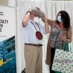 Dr. Brian Postl tries on a hat presented by Melanie MacKinnon on stage at his retirement celebration.