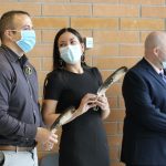 The graduates each hold an eagle feather and wear a braided sweetgrass lapel pin.