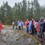 Students stand in the outdoors in ponchos in a land-based learning class.