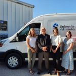 UM staff stand in front of a new electric fleet vehicle.
