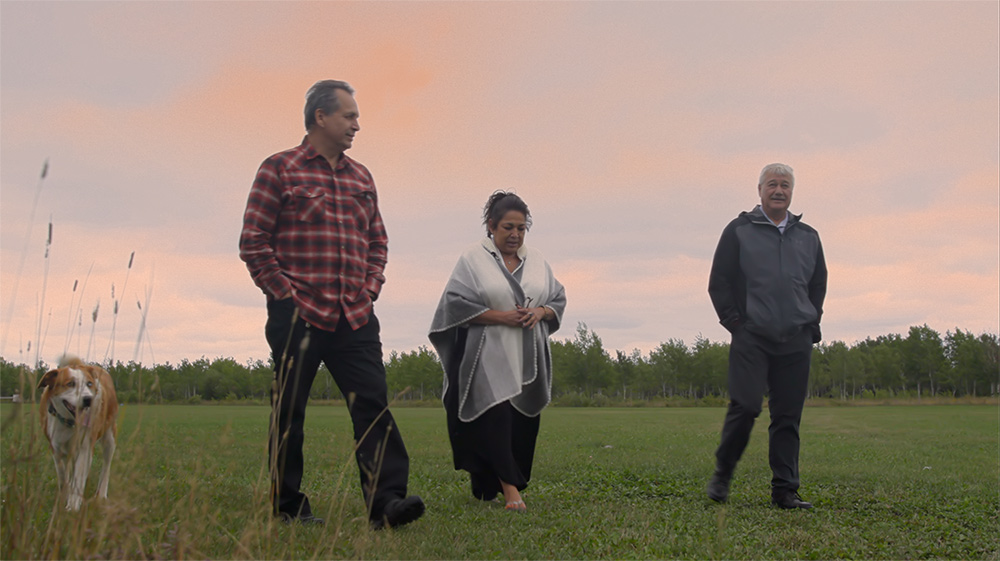 EJ Fontaine, Ardell Cochrane and Robert Maytwayashing walk across a field.