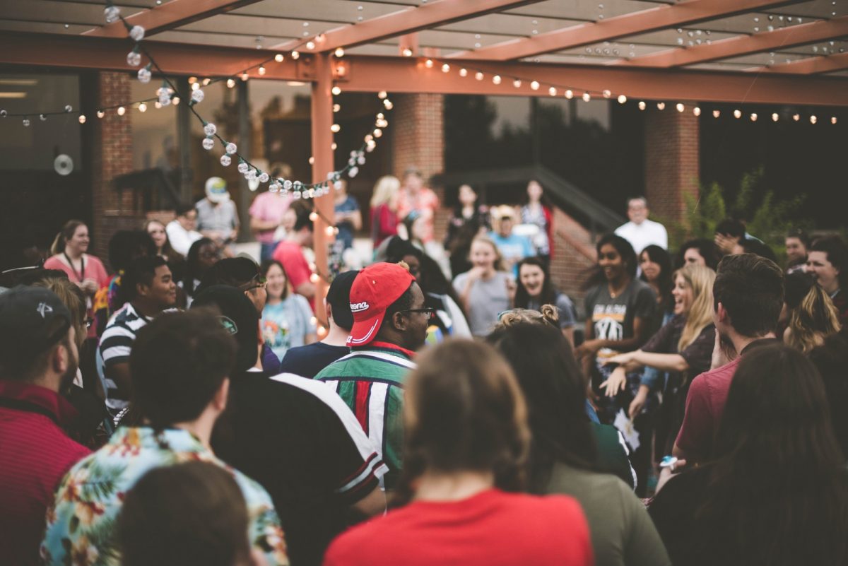 A photo of a group of young people laughing at a party in an outdoor space.