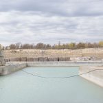 A thin wire hangs across a limestone quarry lake. Image courtesy artist Lisa Stinner-Kun. Title: Garson (hanging wire), 2017, archival ink jet print.