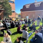 Faculty of Agricultural and Food Sciences students and staff chat at a barbecue in a green space.