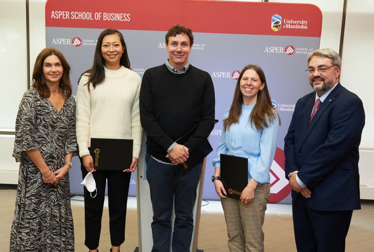 Three women and two men dressed in suits standing in a row.