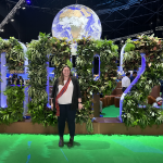 Fiona Lebar stands in front of the COP26 sign, made of plants