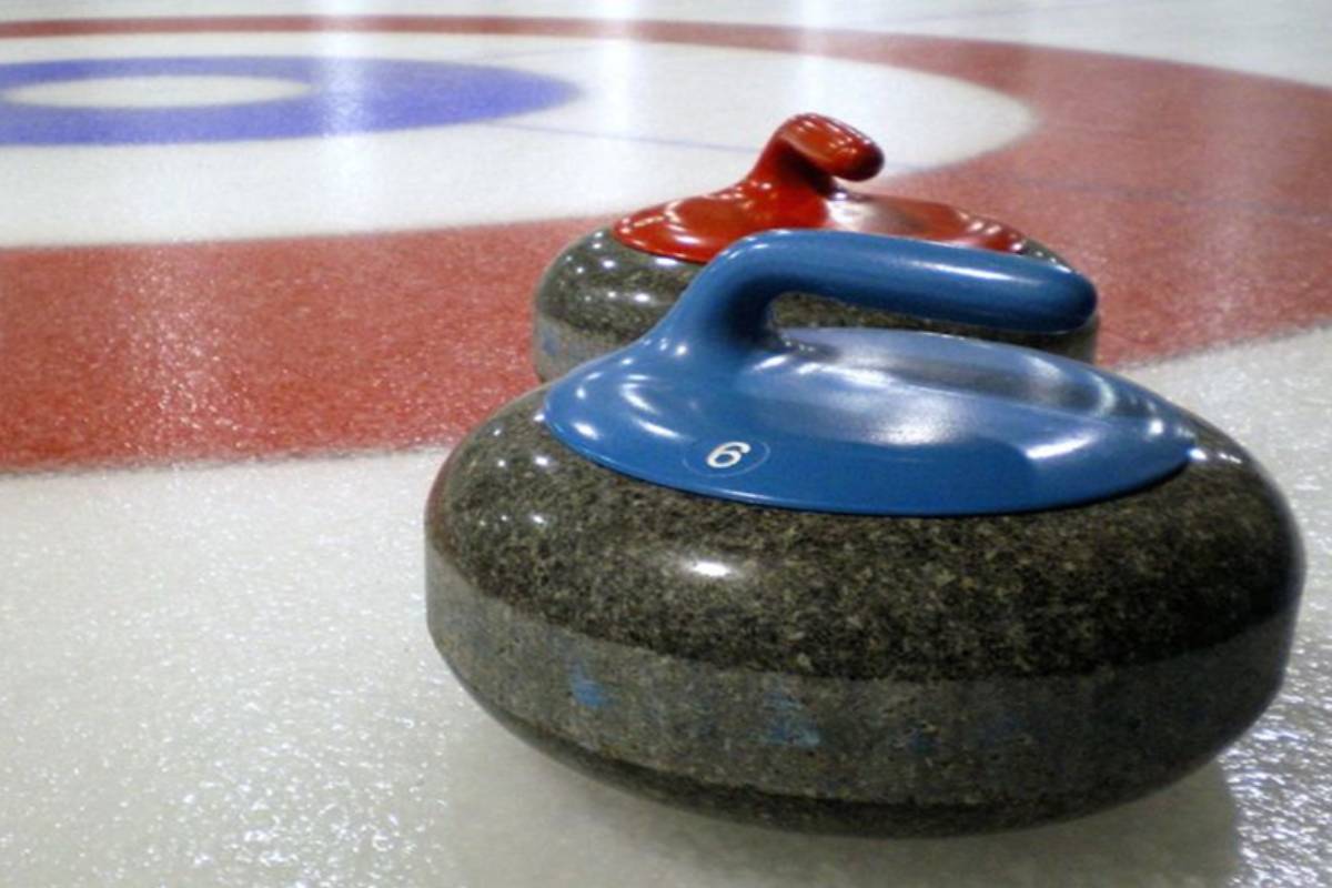 Two curling rocks on ice, one rock has a blue handle, the other is red.