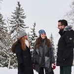 Three students outside in winter with trees in the background.