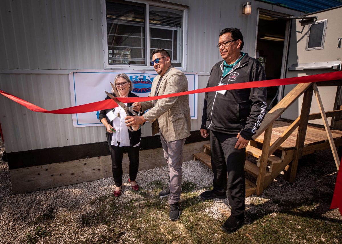 Ribbon is cut by three officials in front of learning hub.