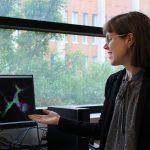 Woman sits a desk, looking at her computer screen.