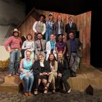 Group of actors in farming costumes on stage.