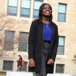 Student stands in front of admin building.