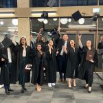 Photo of graduates in gowns tossing caps in the air.