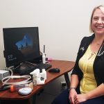 Karen McElroy sits at her desk with several respiratory therapy devices.