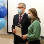 Dr. Vercaigne and Shaelyn pose for a photo. Dr. Vercaigne is holding five certificates. Balloons in UM's colours are on either side of them.