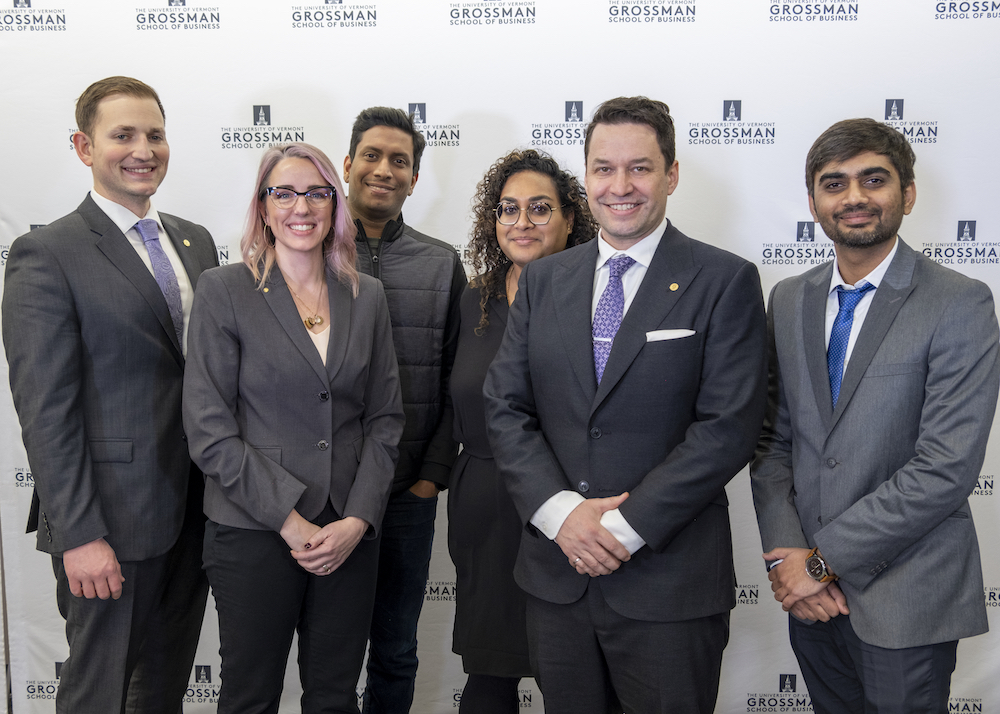 Four males and two females dressed in business suits standing together