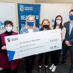 Representatives from UM and Bell Let's Talk hold a large cheque for $100,000