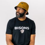 Ogo Okwumabua sitting with a hat on and a Bison T-shirt