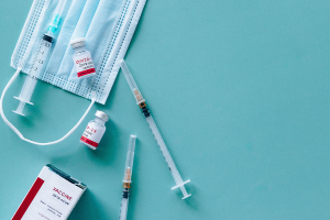 photo of 2 needles, 2 vaccine bottles and a mask