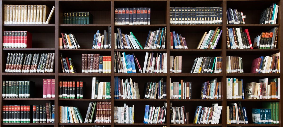 A library book shelf filled with books of various sizes, colours and widths.