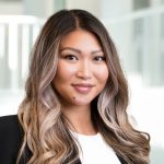 Woman wearing white shirt and black blazer smiling.