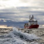 Amundsen icebreaker ship in open water with dark clouds in the sky.