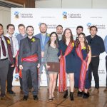 12 people gathered in front of the University of Manitoba banner.