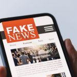 Photo of hand holding a cell phone with Fake News on the screen.