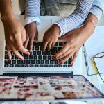 Birdseye view of parents and childs hands over a laptop keyboard.