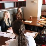 A group of female students in a discussion with Indigenous health leaders at a table.