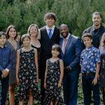 Photo of a family group of 10 people smiling by trees.
