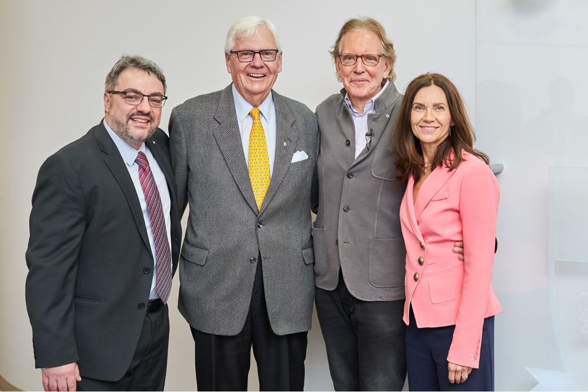 three men and one woman pose in business attire pose for a photo